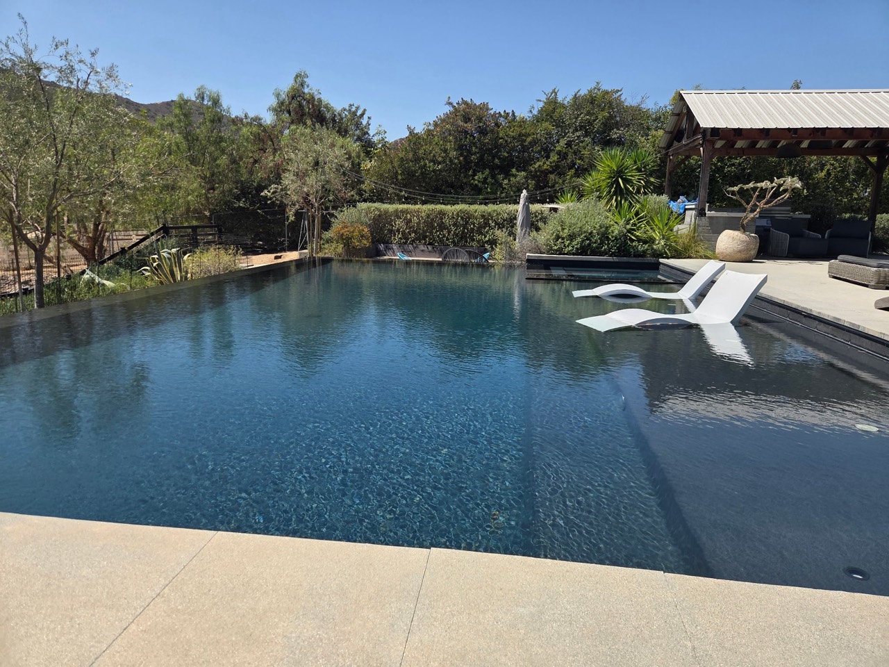 Backyard swimming pool with in-water loungers and a shaded patio
